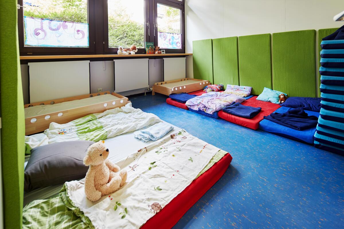 Group room with large play corner with carpet, various seating and toys in the daycare center Löwenzahn