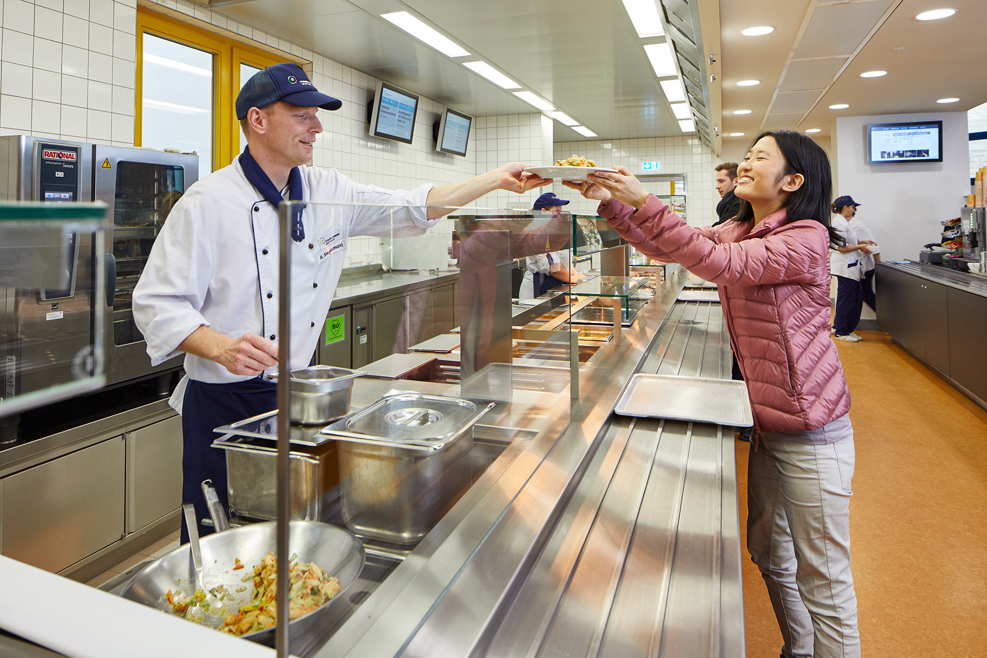 A staff member hands the food plate to the student at the counter 