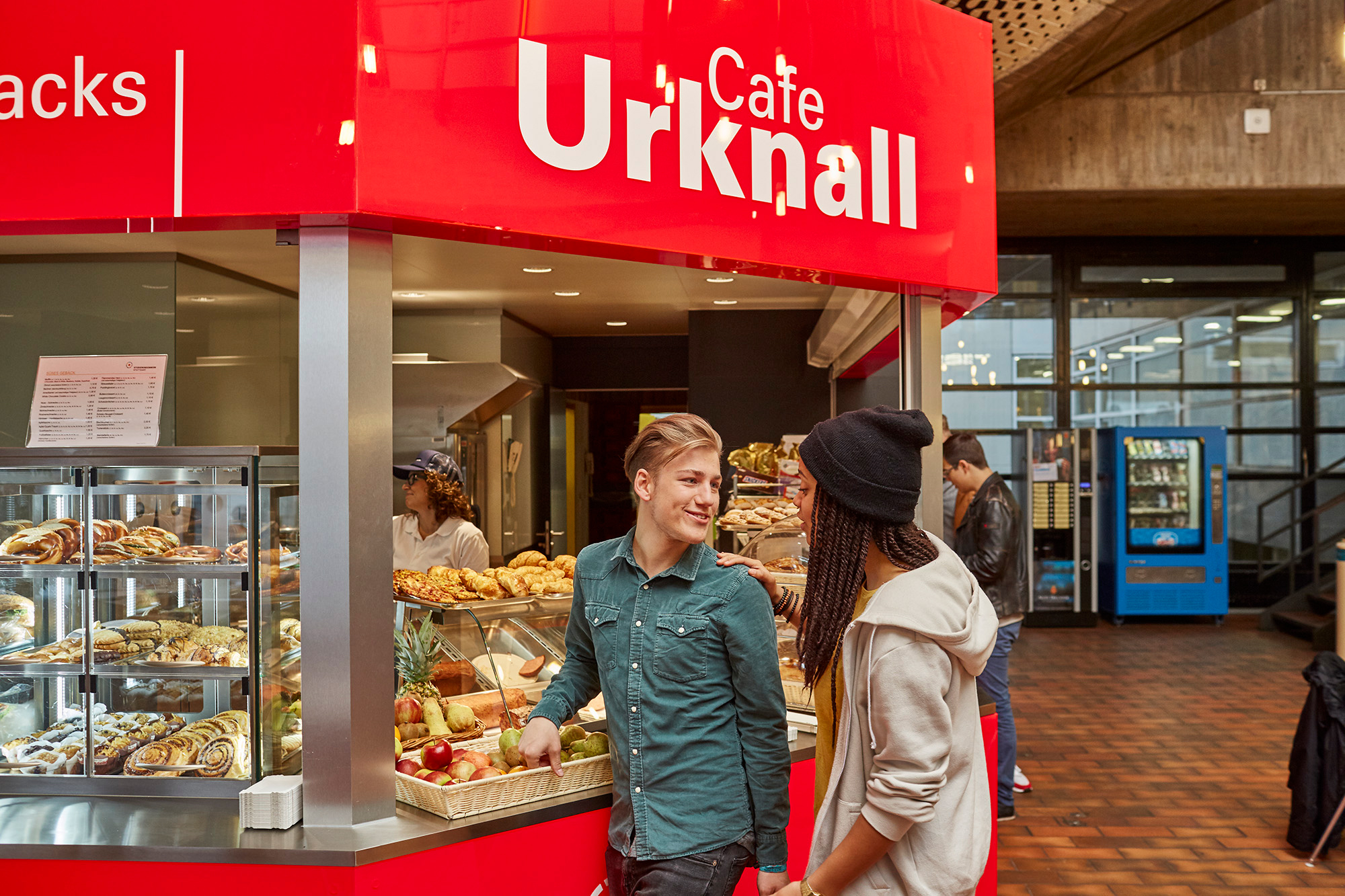 Studierende unterhalten sich an der Theke der Cafeteria Urknall