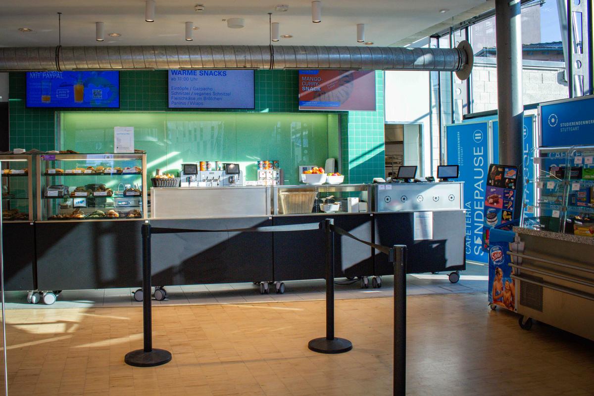 Theke mit Snacks. Darüber hängen Bildschirmen, die Infos rund um das Studierendenwerk anzeigen.