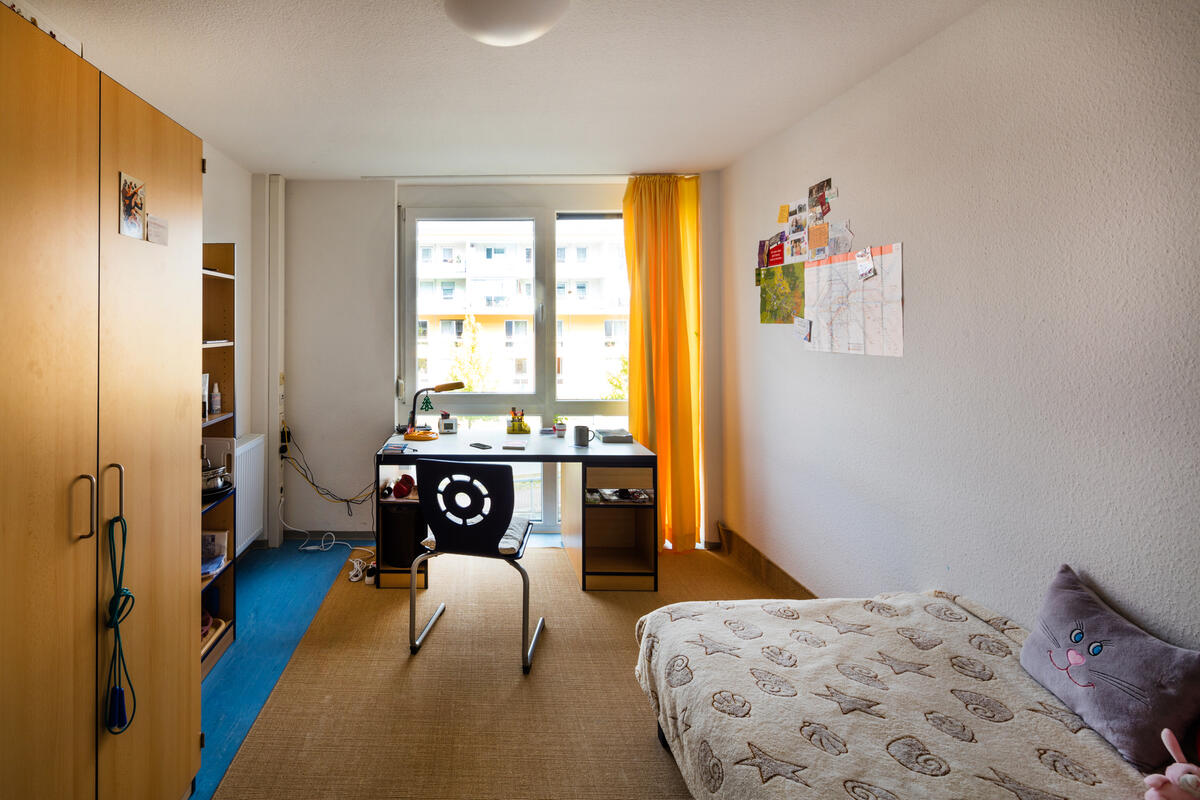 Room with bed, desk and wardrobe in Filderbahnplatz residential complex