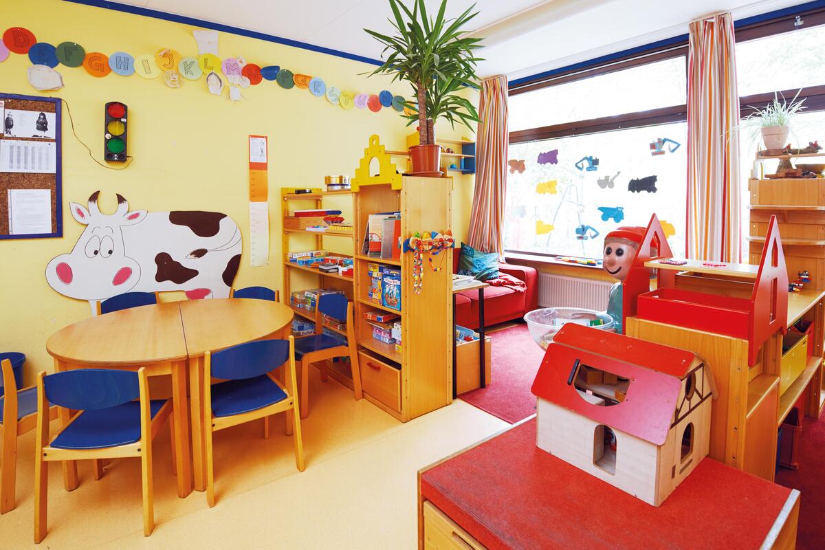Gruppenraum mit Tisch und Stühlen sowie Sitzecke im Kinderhaus Uni-Kids