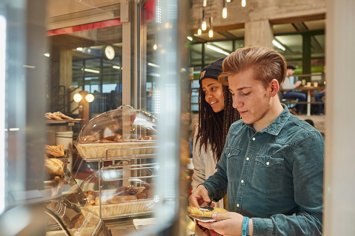 Student chooses a bread product at the counter of the cafeteria Urknall