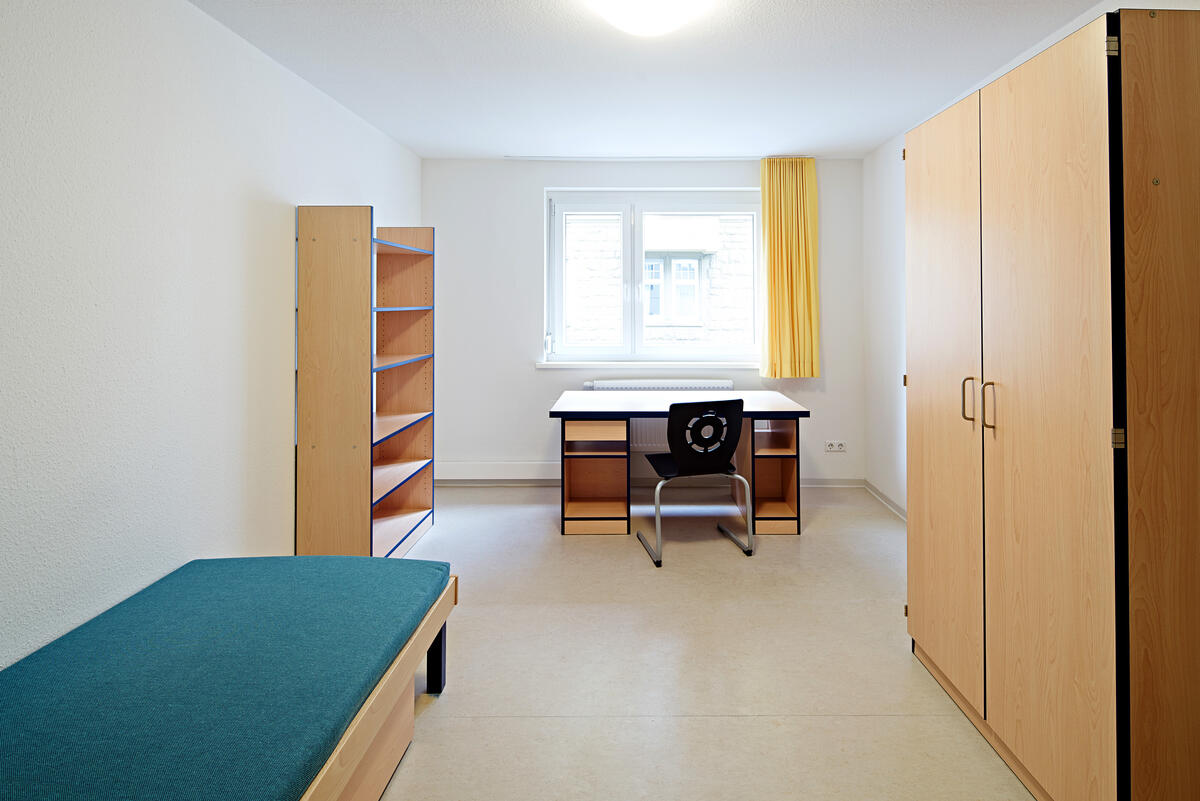 Zimmer mit Bett, Schrank, Regal und Schreibtisch im Wohnheim der Rieckestraße