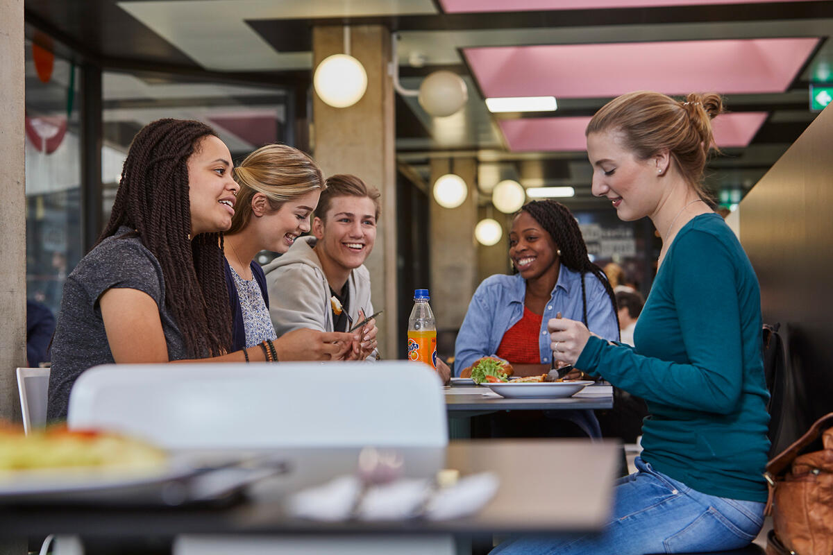 Students eat together at the table in the  cafeteria Contrast