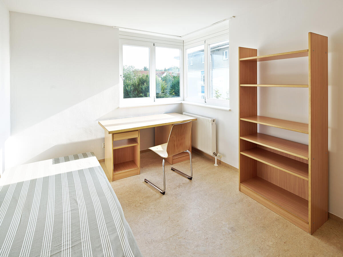 Zimmer im Studentendorf Ludwigsburg mit Bett, Schreibtisch und Regal