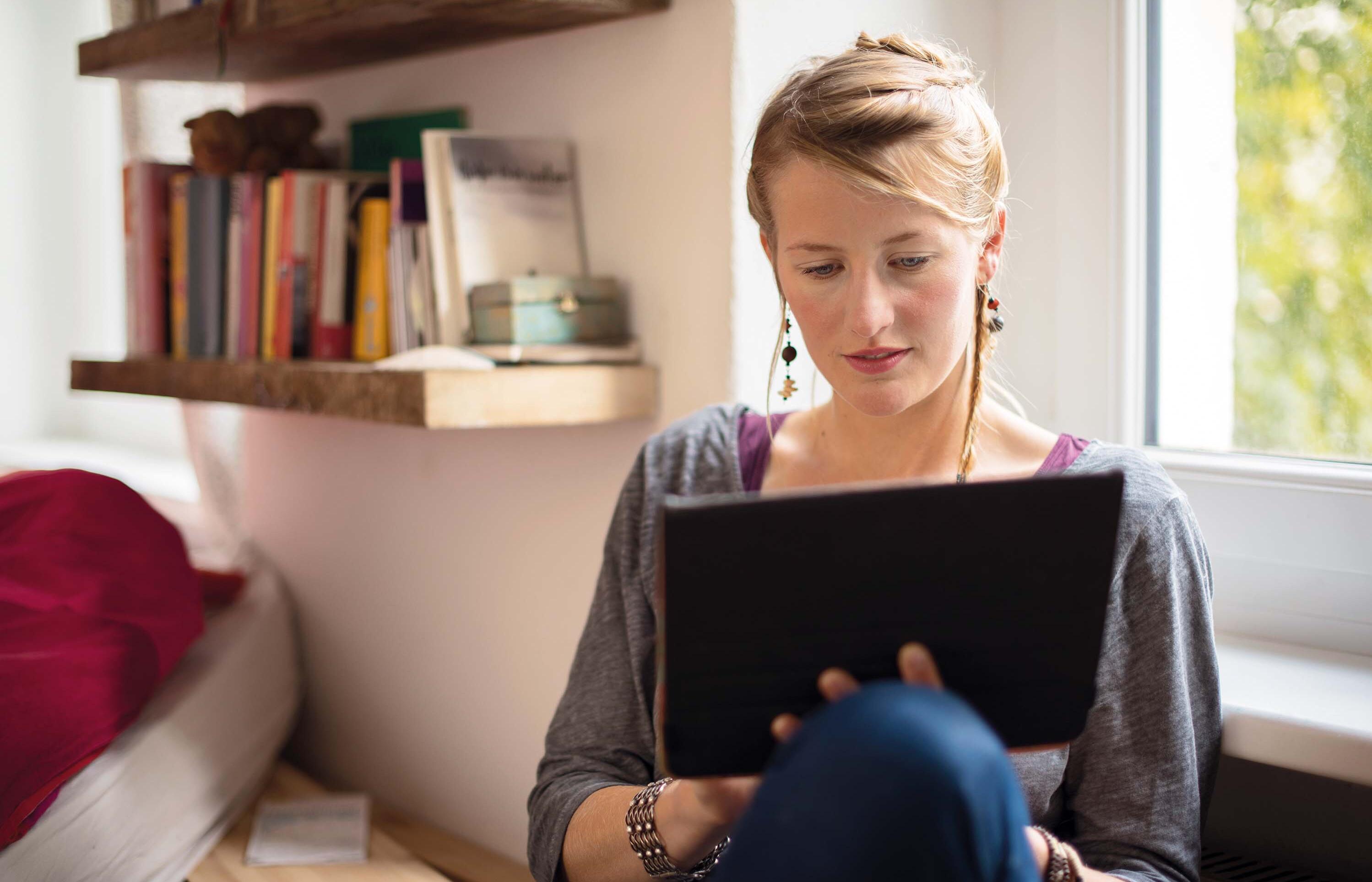 Studentin sitzt konzentriert am Tablet