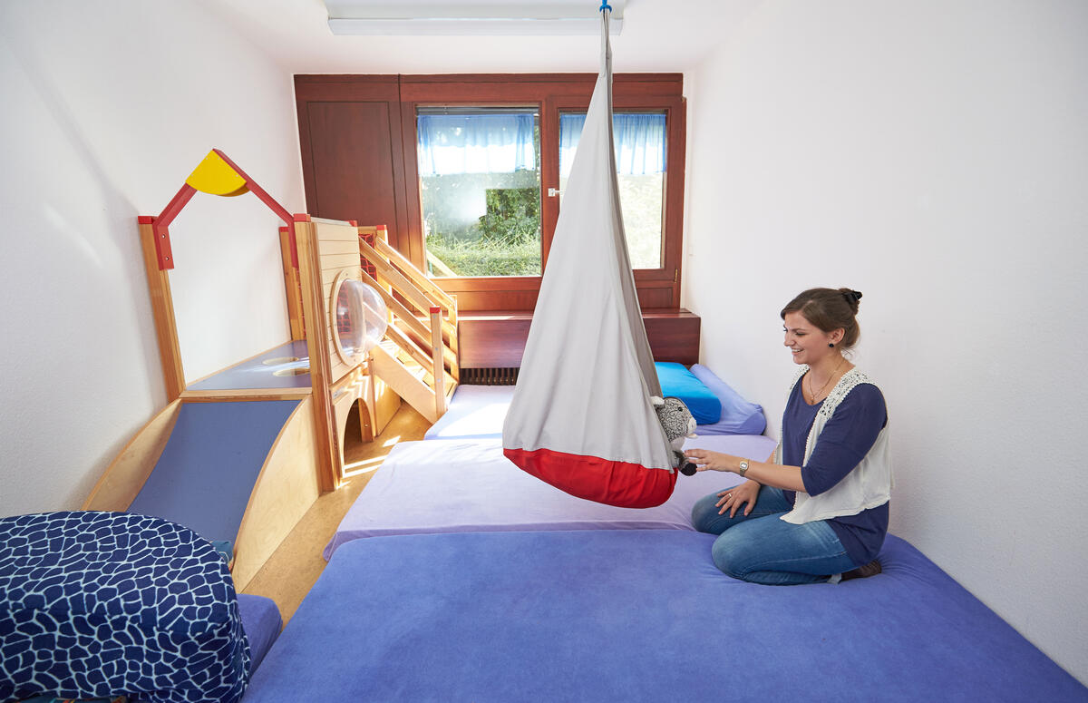 Bedroom with educator in the Kita Hochschulzwerge. Also visible is a children's tent, beanbag and a small playhouse