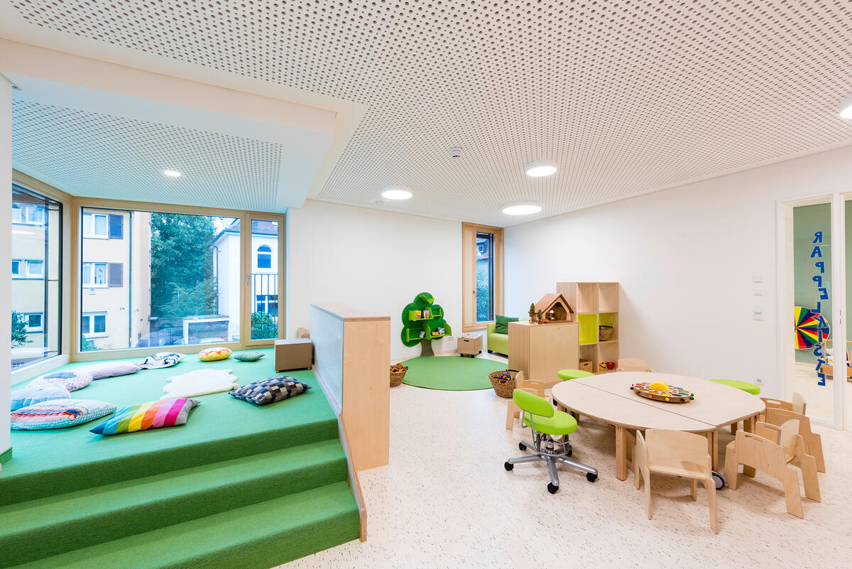 Group room with table and chairs and play corner with pillows and building blocks
