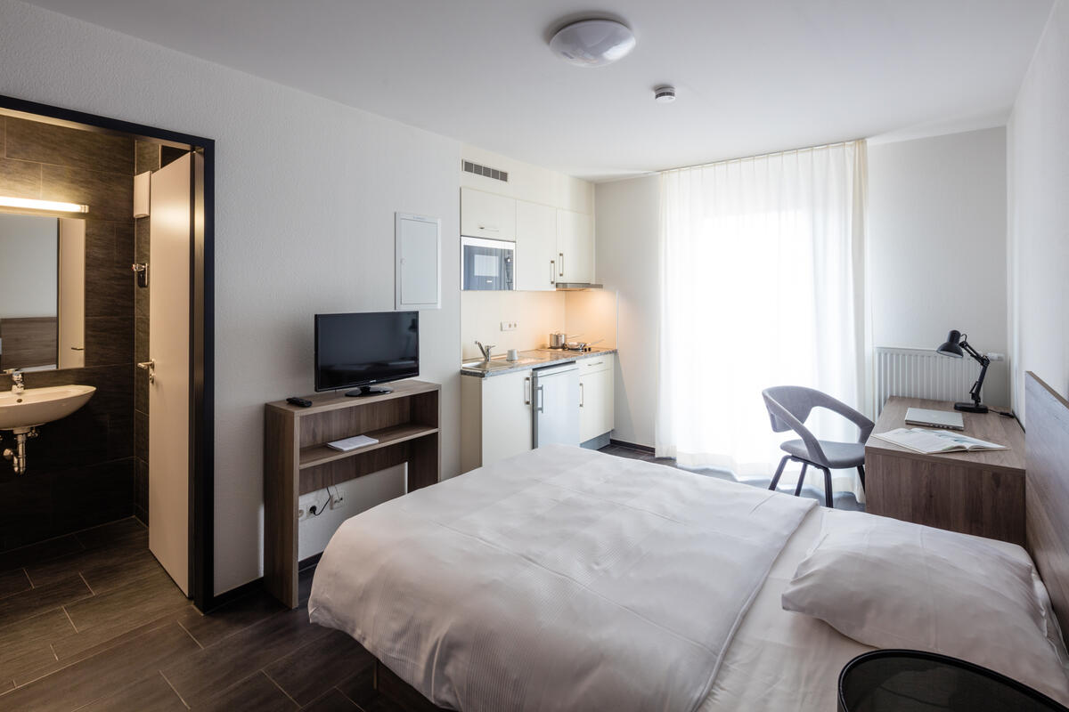 Zimmer mit Bett, Schreibtisch und Fernseher im Boardinghaus in Esslingen