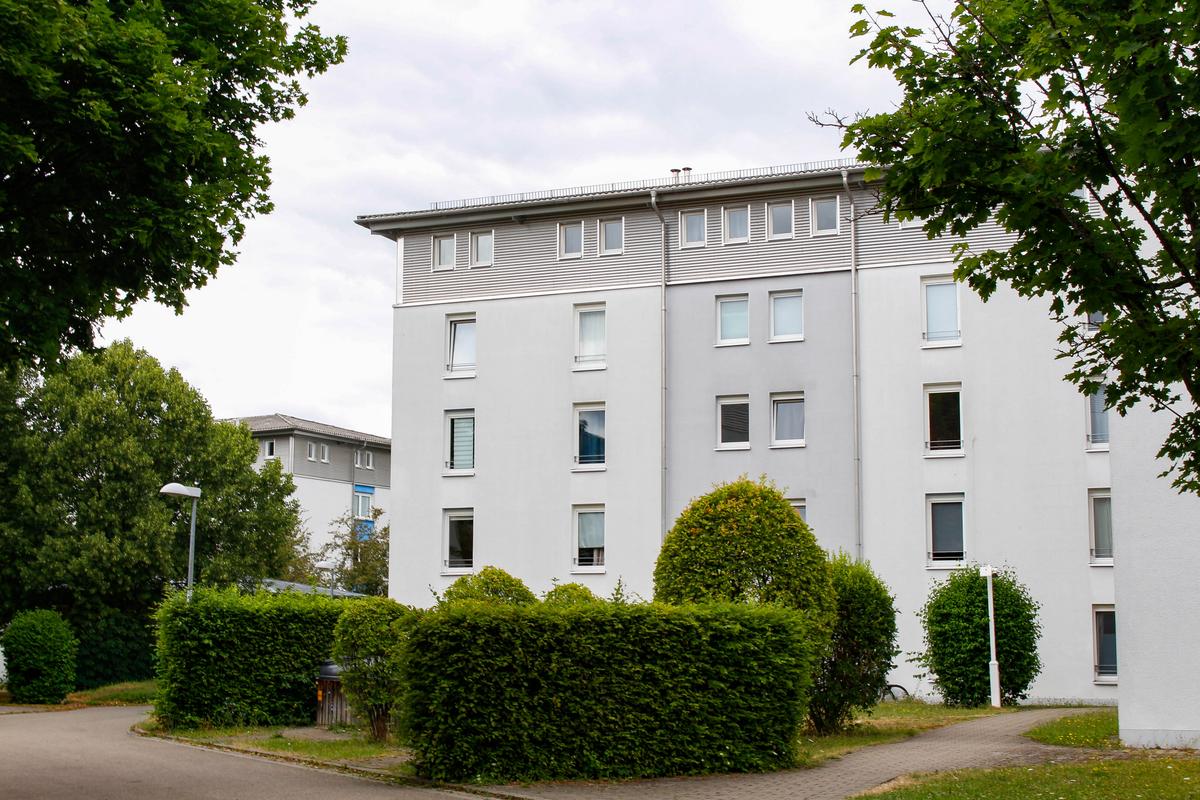 Weißes Gebäude des Studentendorf Ludwigsburg. Es sind davor Hecken und Bäume zu sehen