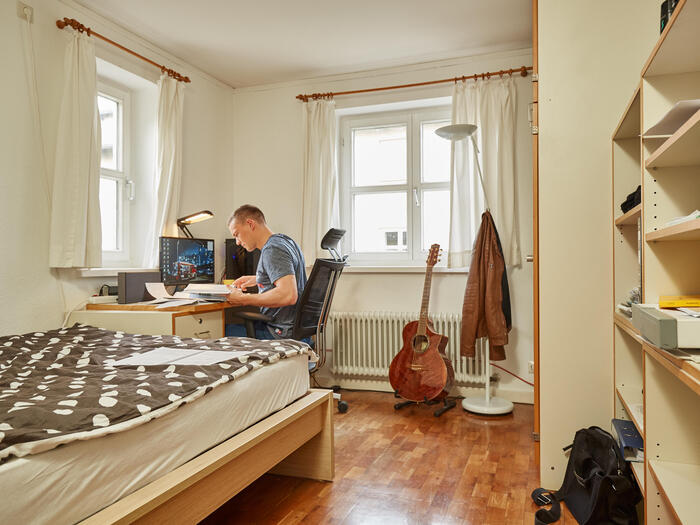 Student sitzt an seinem Schreibtisch in seinem Wohnheimszimmer und lernt