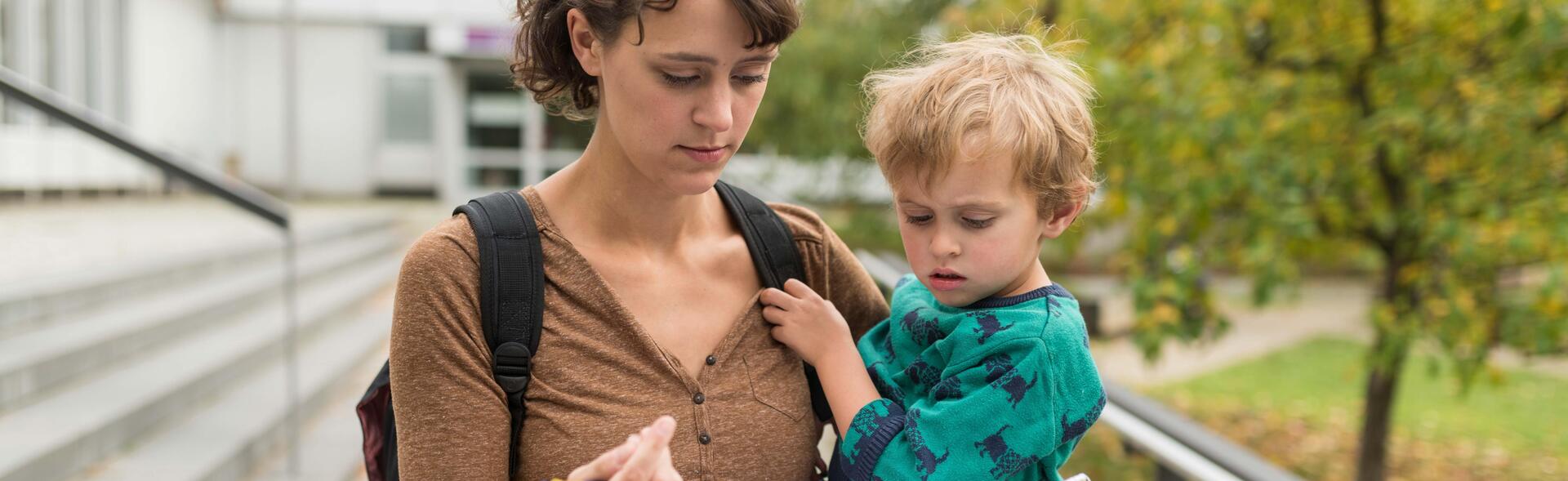 A student holds her child in her arms and fills out a form