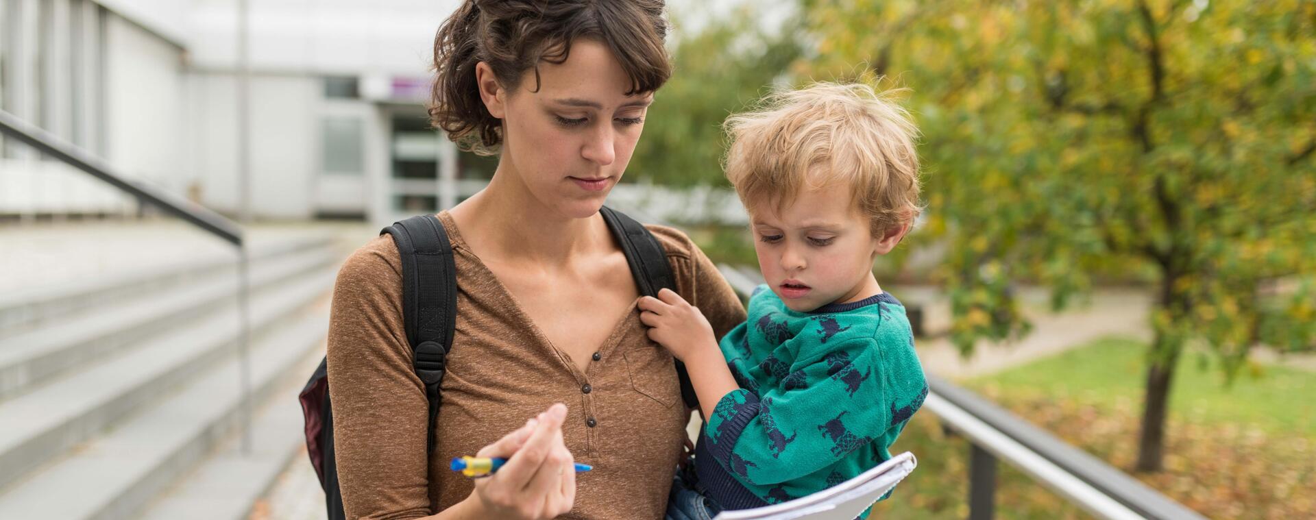A student holds her child in her arms and fills out a form