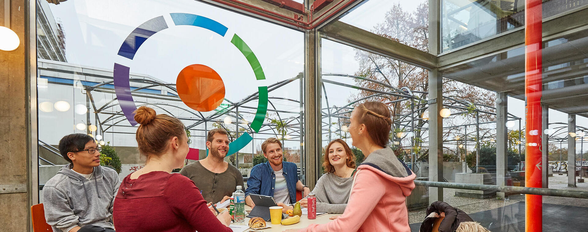 Studierende sitzen am Tisch zusammen und unterhalten sich