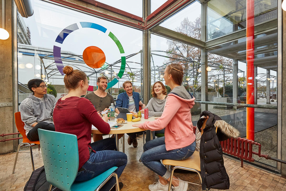 Studierende sitzen am Tisch zusammen und unterhalten sich