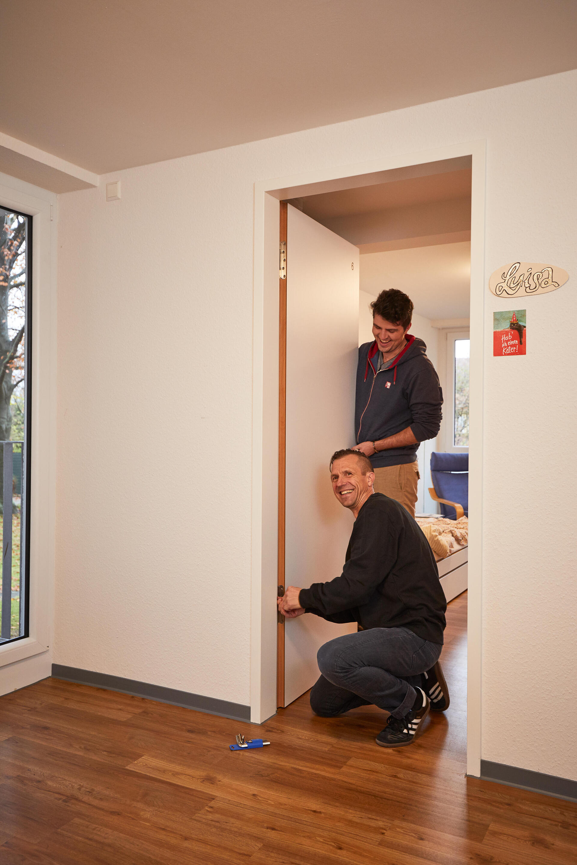 Hausmeister repariert Türe eines Zimmers im Studentenwohnheim