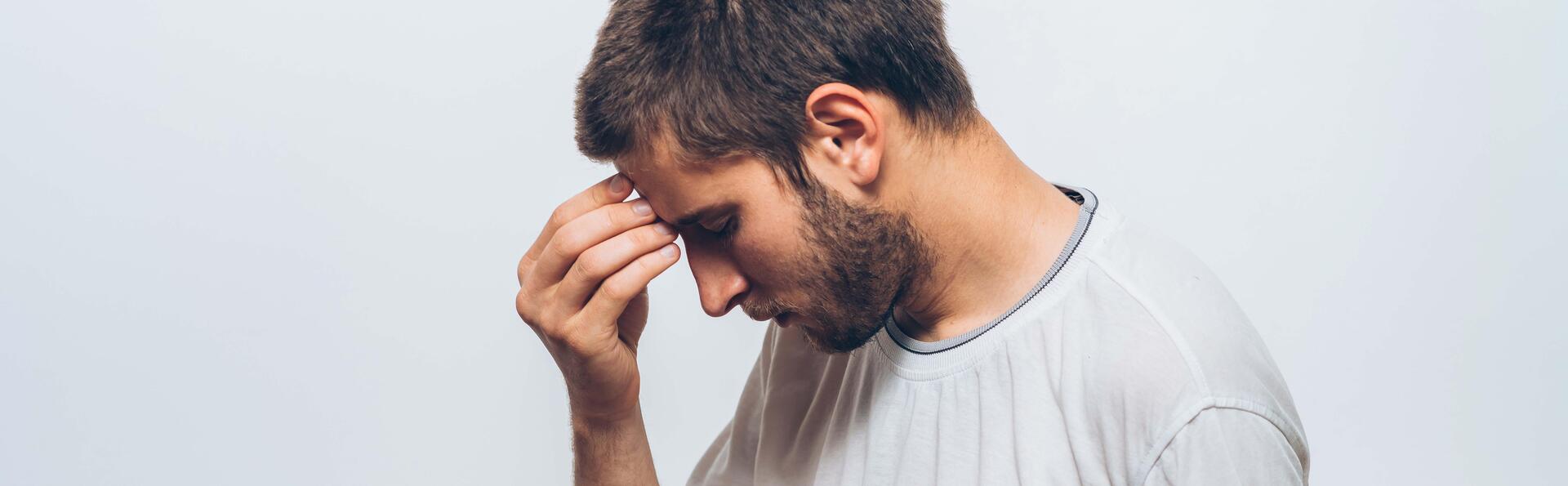 Young man has a headache and holds his hand to his forehead