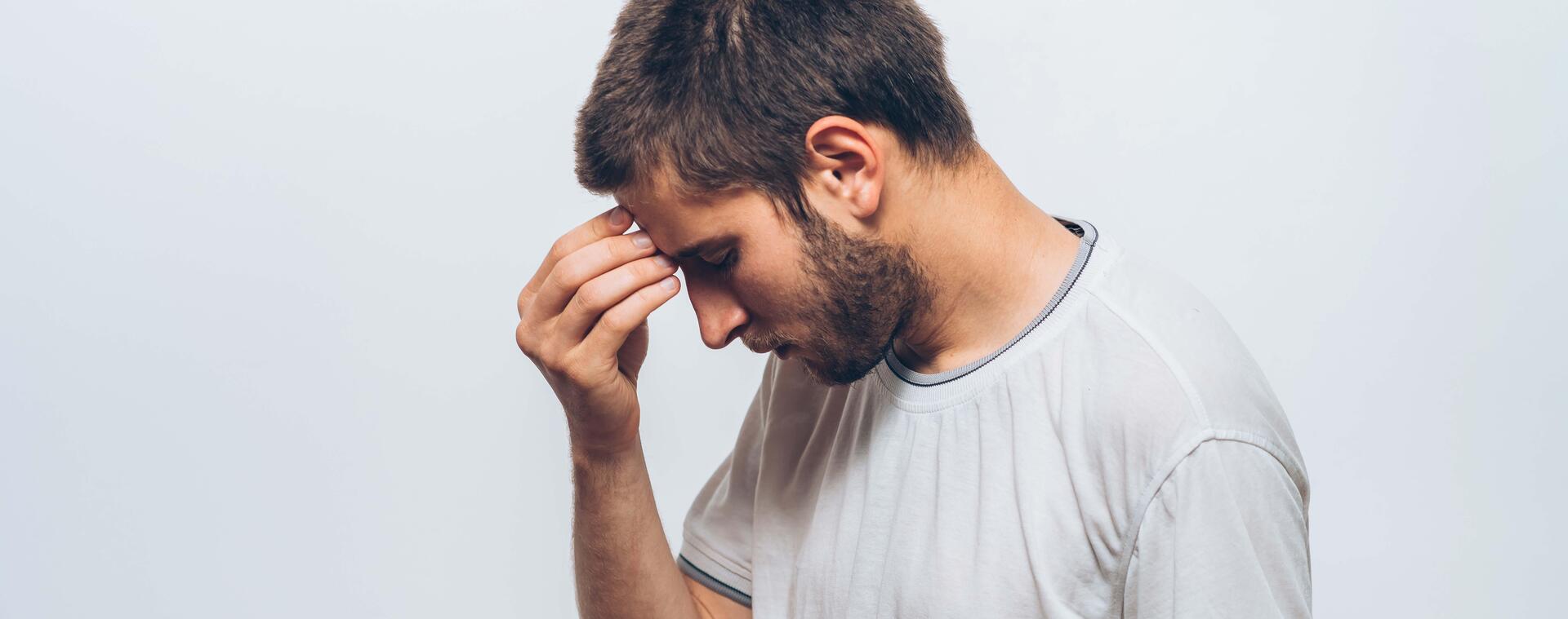 Young man has a headache and holds his hand to his forehead