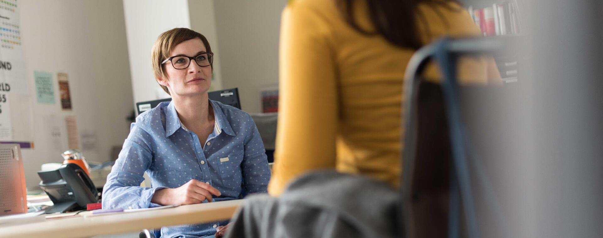 Sozialberaterin berät Studentin im Rollstuhl