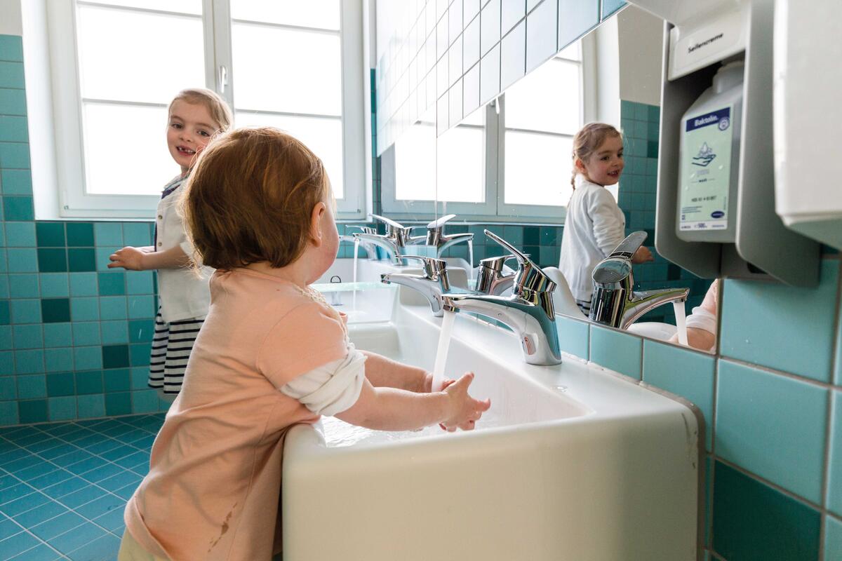 Two children wash their hands in the bathroom of the Villa MiO day care centre