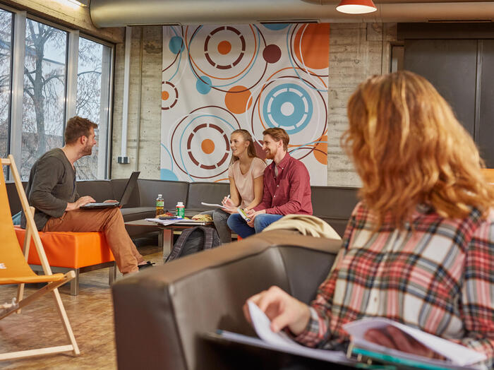 Studierende halten sich in der Cafeteria Denkpause auf. Zum lesen oder zum miteinander unterhalten