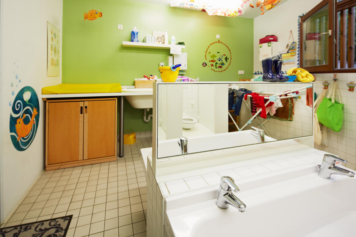 Bathroom with changing table, washbasin, shelf and mirror at the Pfaffenwald daycare center