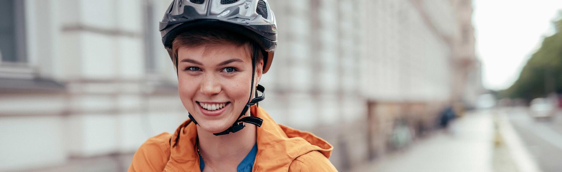 Studentin mit Fahrradhelm schiebt ihr Fahrrad