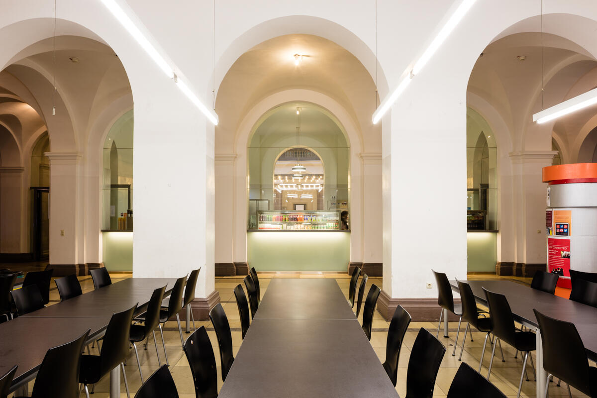 Interior view of the HfT cafeteria with long tables and round arches.