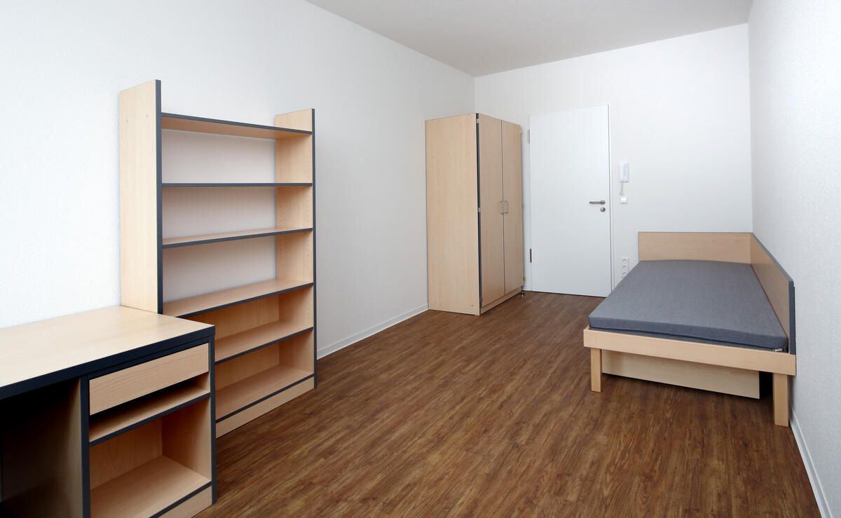 Zimmer mit Bett, Regal und Schreibtisch im Wohnheim in der Heilmannstraße 3