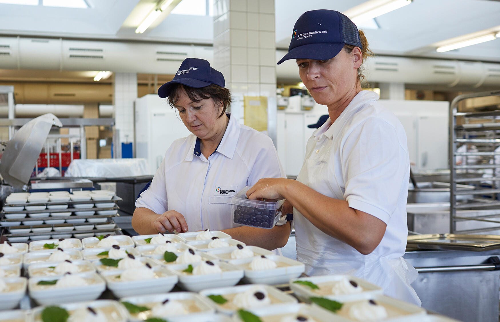 Zwei Küchenmitarbeiterinnen verfeinern das zubereitete essen