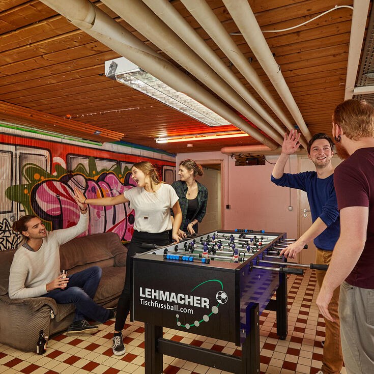 Studierende spielen Tischkicker im Gruppenraum