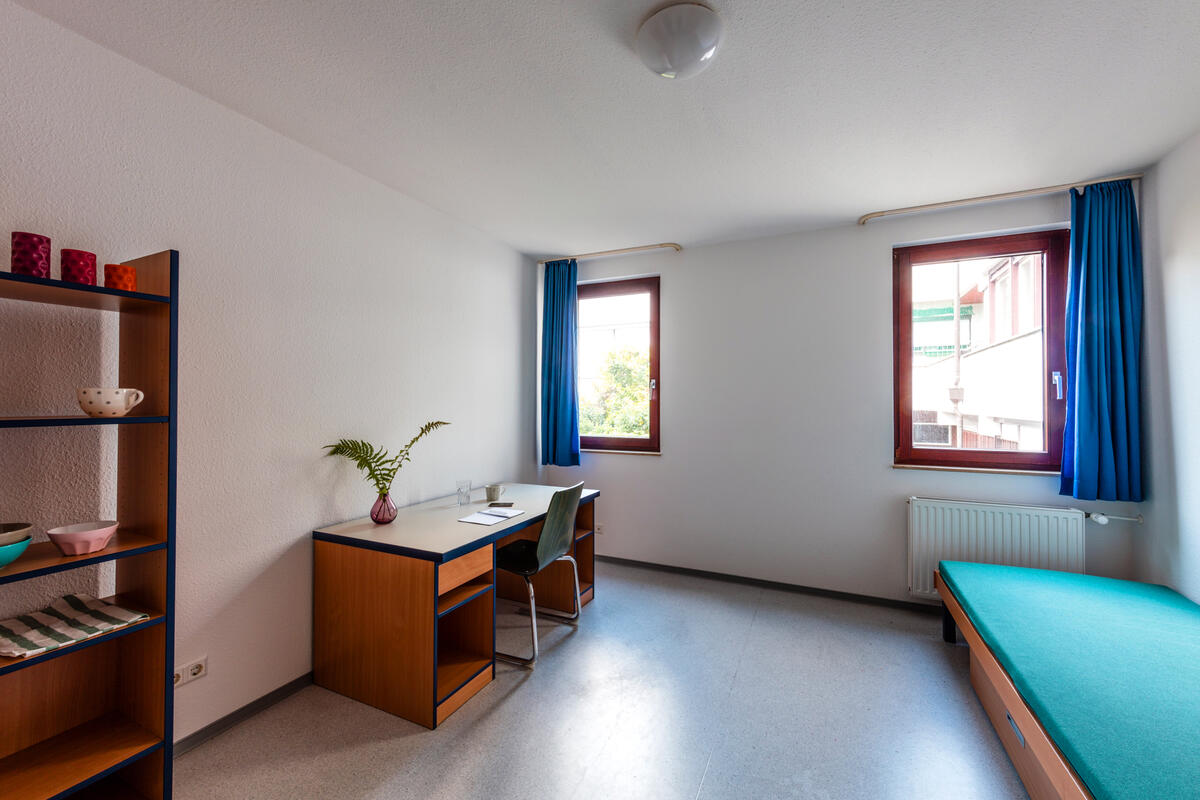 Zimmer mit Bett und Schreibtisch im Wohnheim in der Brückenstraße