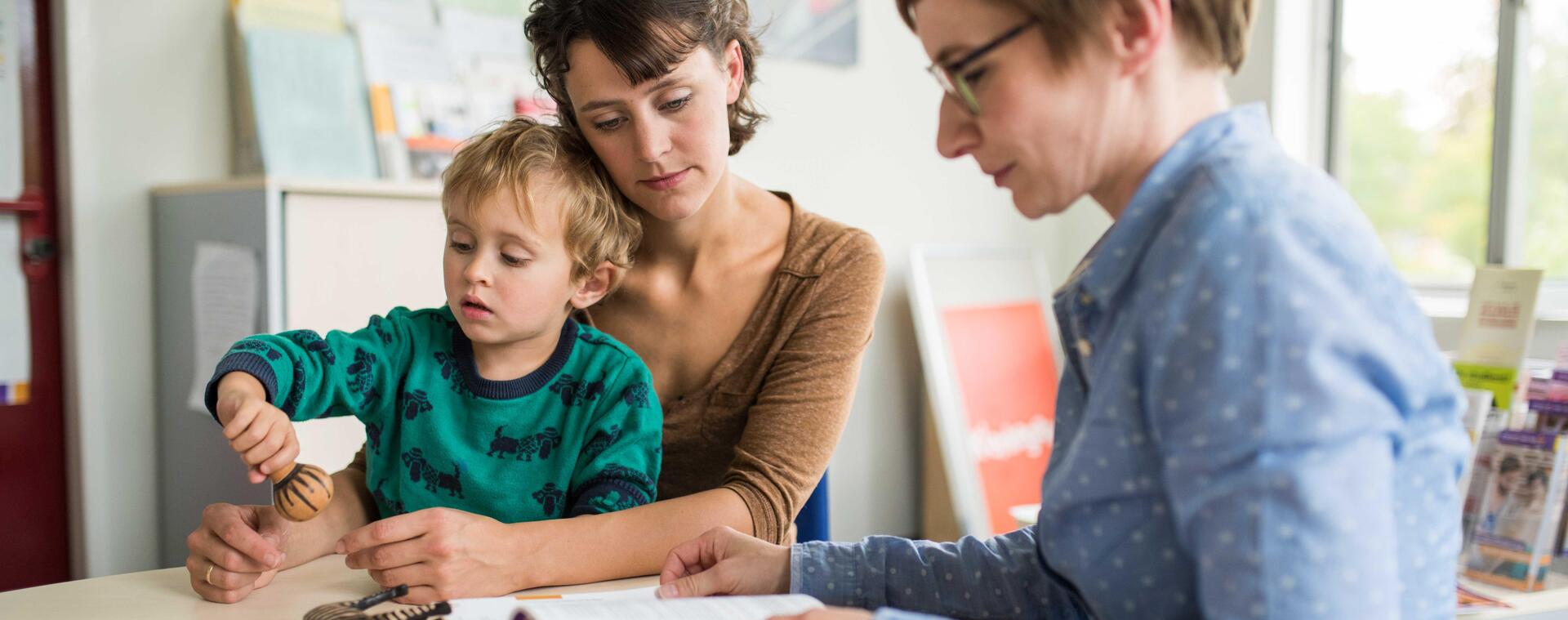 A student gets advice from a staff member of the student union and has her child on her lap