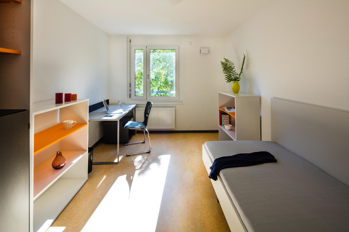 Zimmer mit Bett, Schreibtisch und Regal im Wohnheim in der Rosensteinstraße