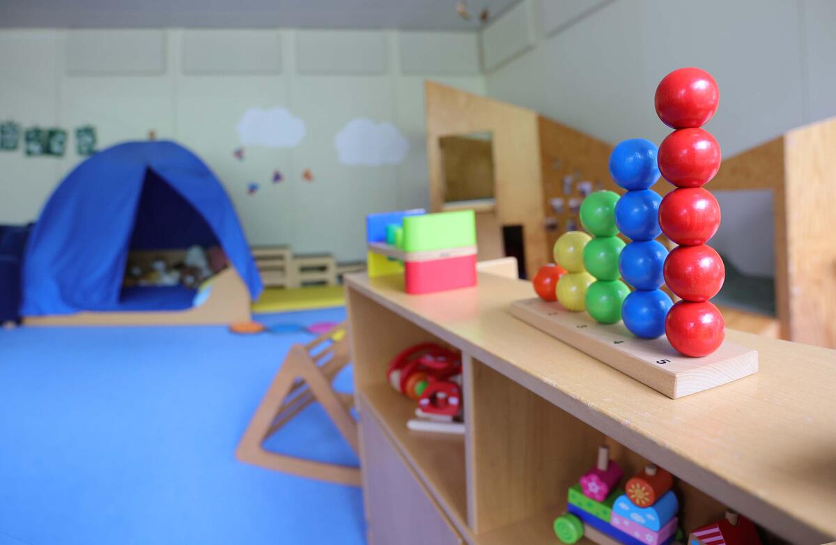 Foto vom Spielzeug in den Räumlichkeiten der Kita Krabbelmäuse. Vorne ist ein Steckspiel zu sehen. Im Hintergrund ist ein blaues Zelt. 