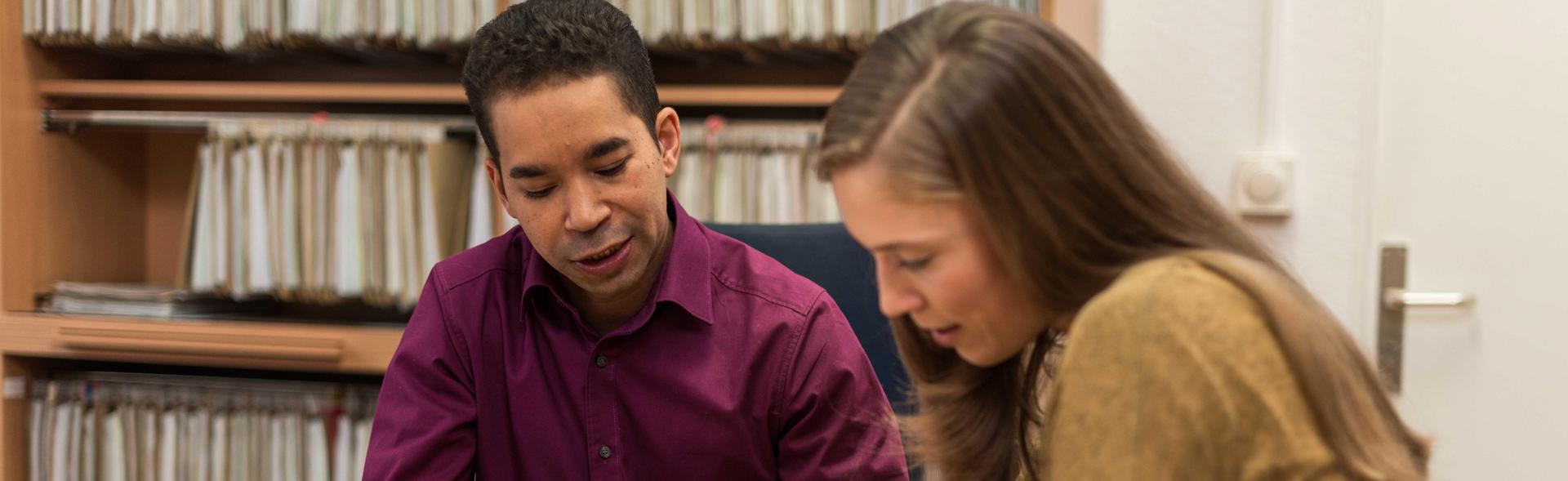 Ein Mitarbeiter des Studierendenwerks berät eine Studentin zum Thema BAföG in einem Büro