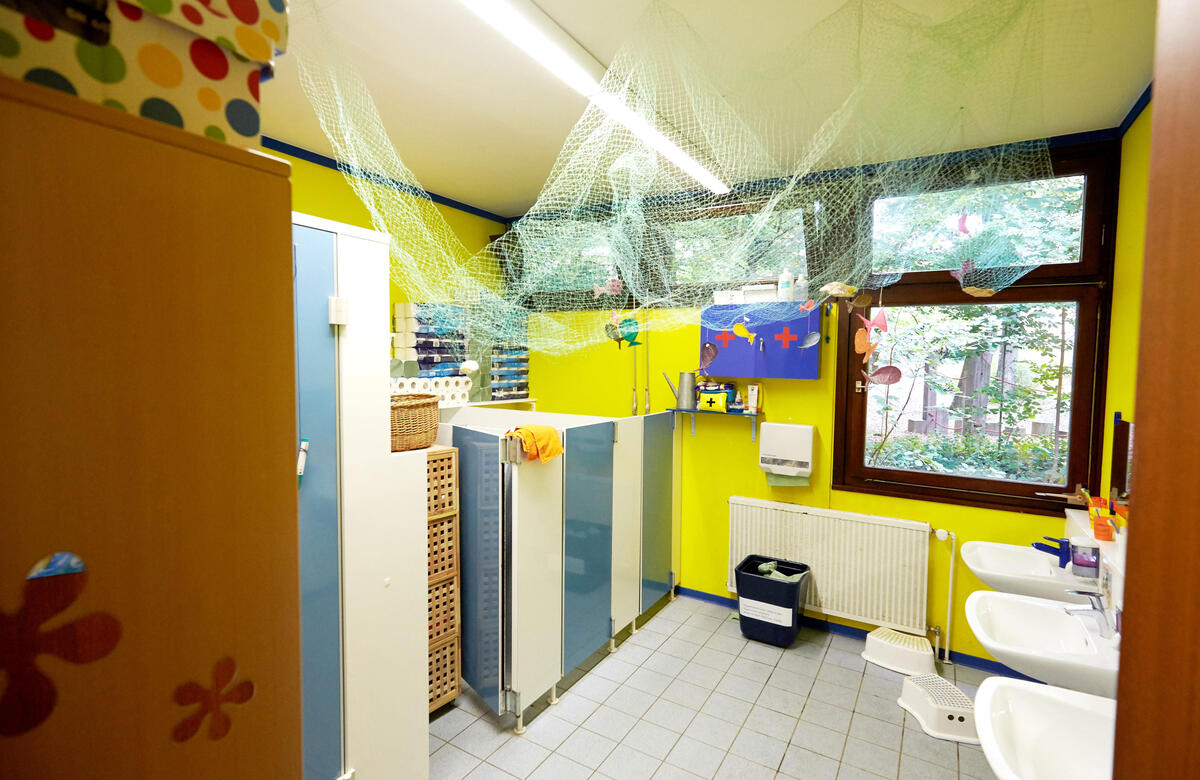 Bathroom with toilet, sink and large window in the children's house Uni-Kids